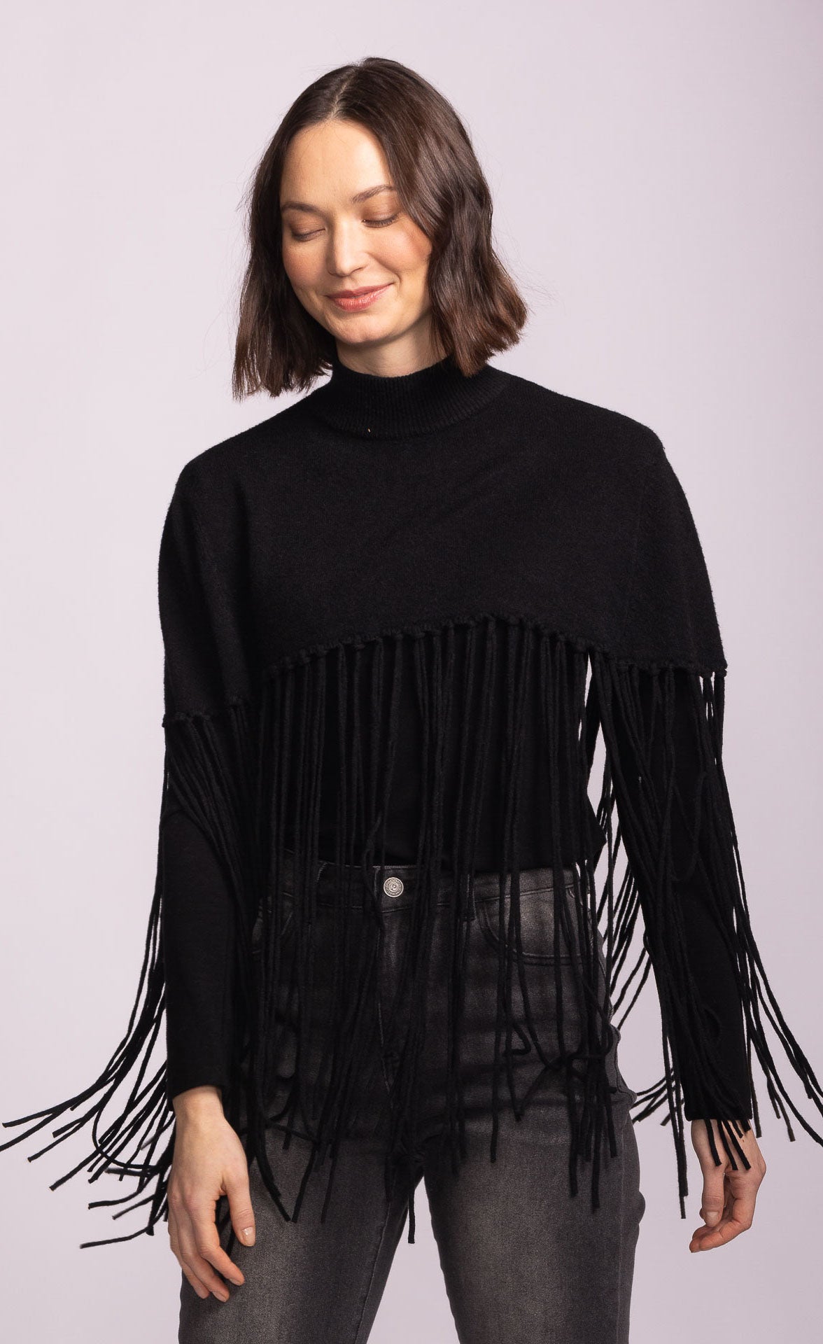 Woman wearing a black fringed sweater against a light purple background