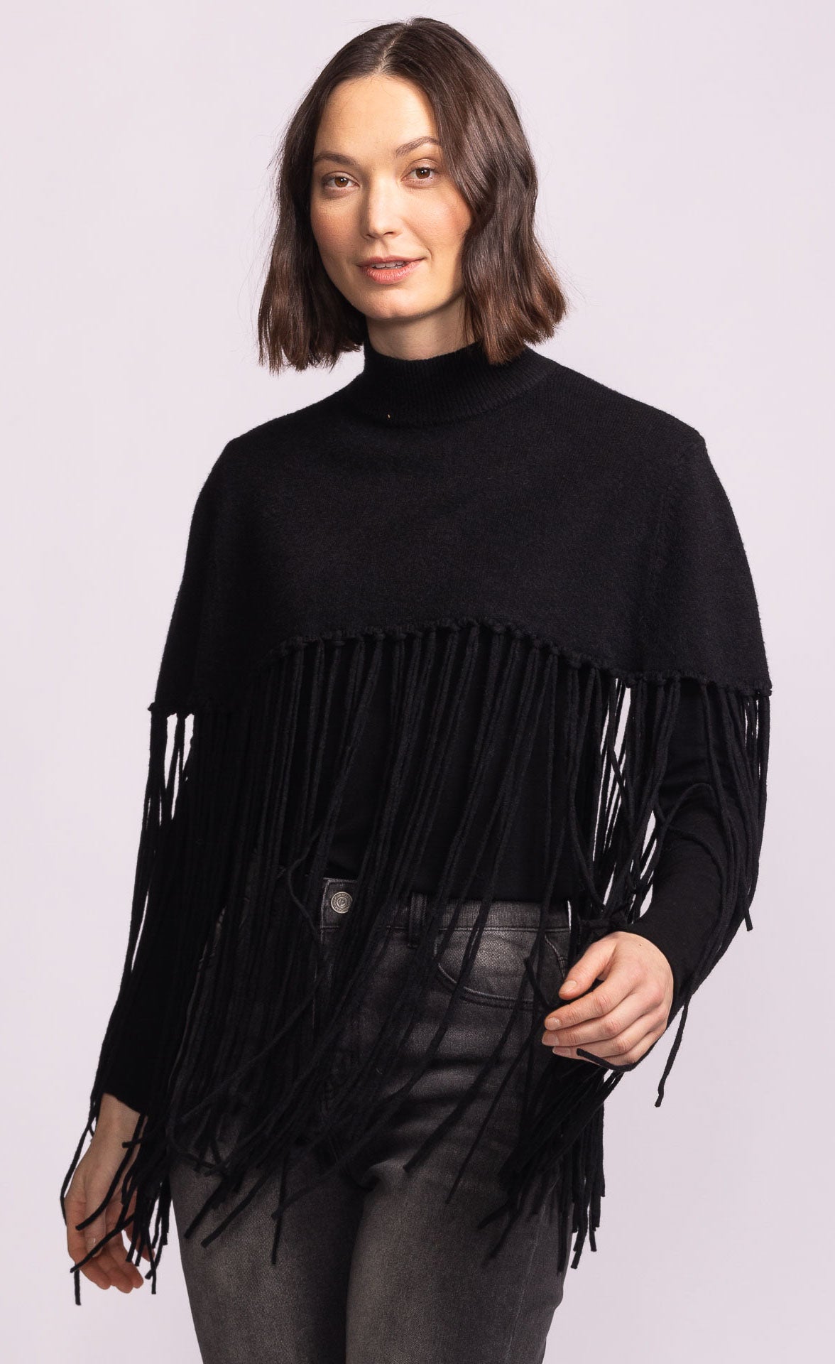 Woman wearing a black fringe sweater against a light purple background