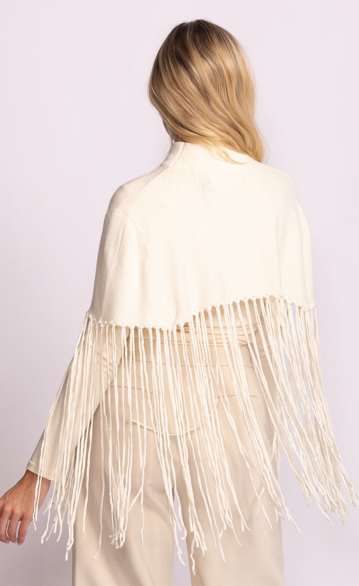 Woman wearing a beige fringe jacket on a light purple background