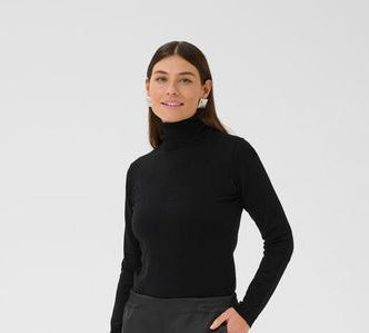 Woman wearing a black turtleneck and gray wide-leg pants on a white background