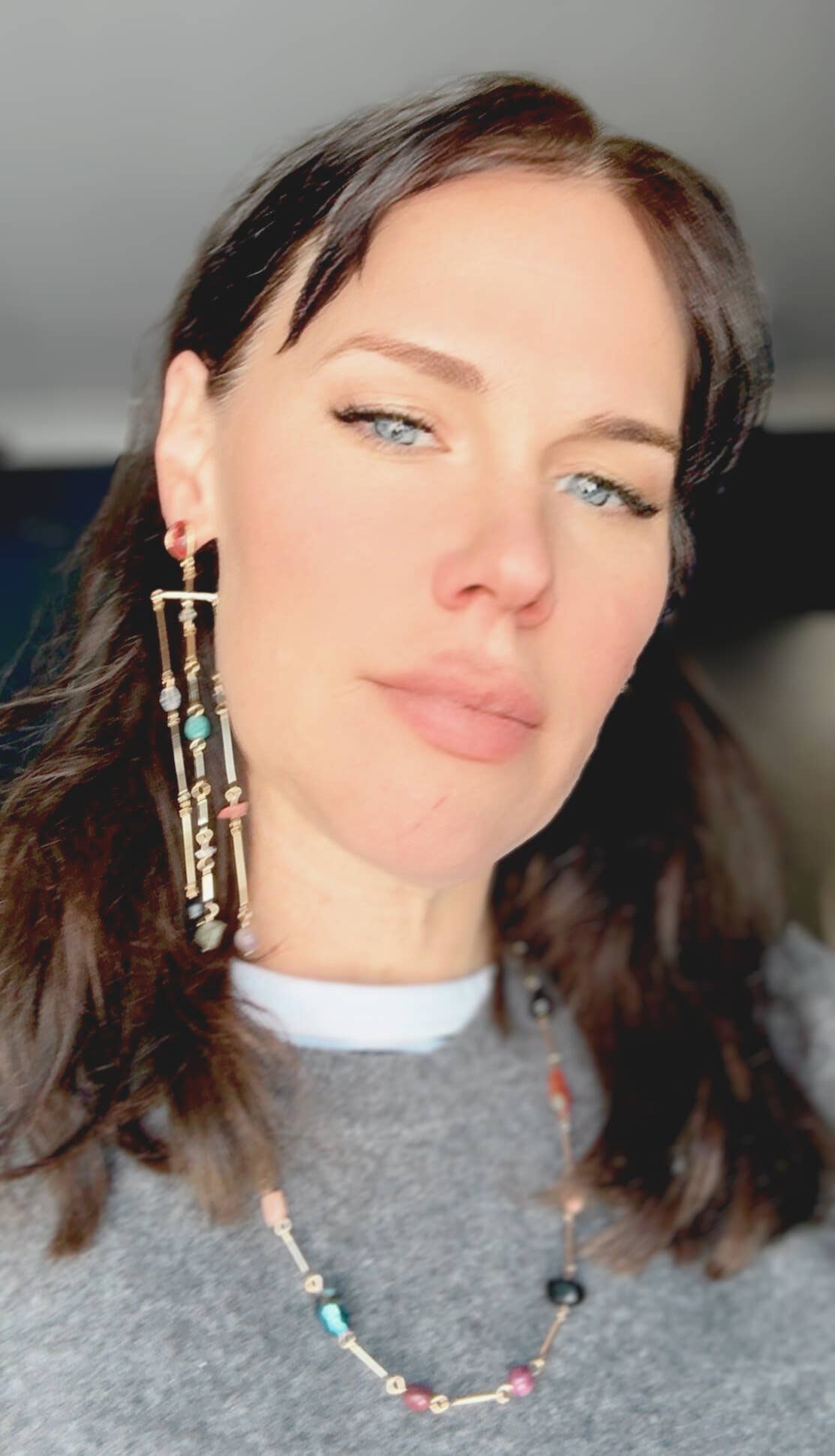 Woman wearing earrings and a necklace with a blurred background
