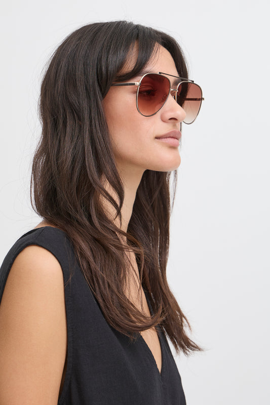 Woman wearing aviator sunglasses with a plain background