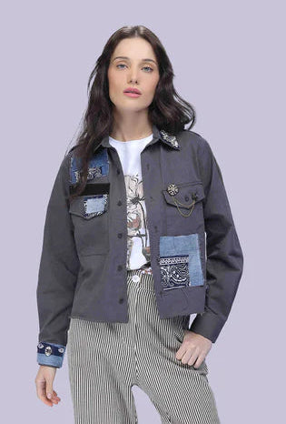 Person wearing a dark denim jacket with patchwork design on a light gray background