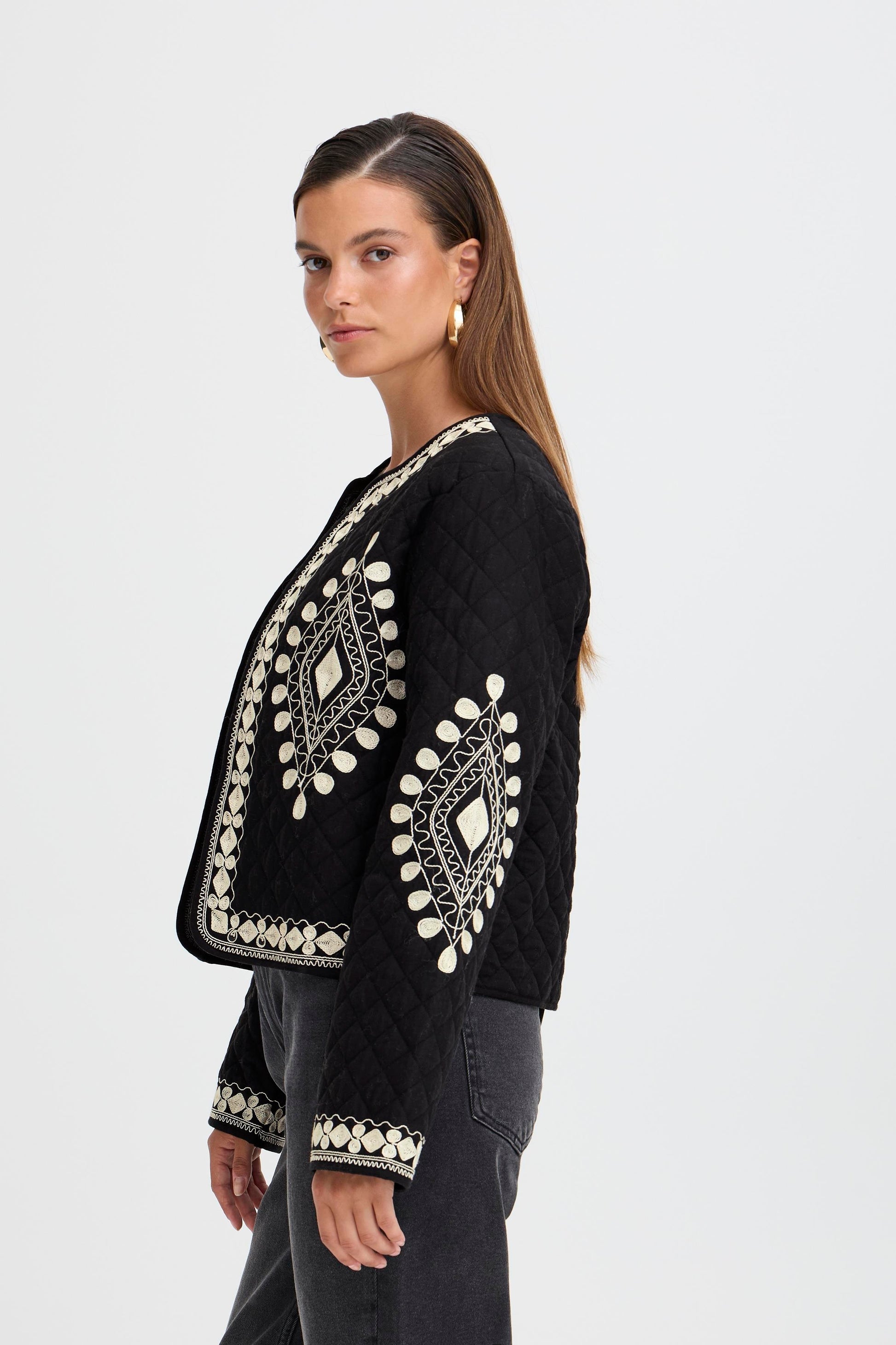 Woman wearing a black embroidered jacket on a white background