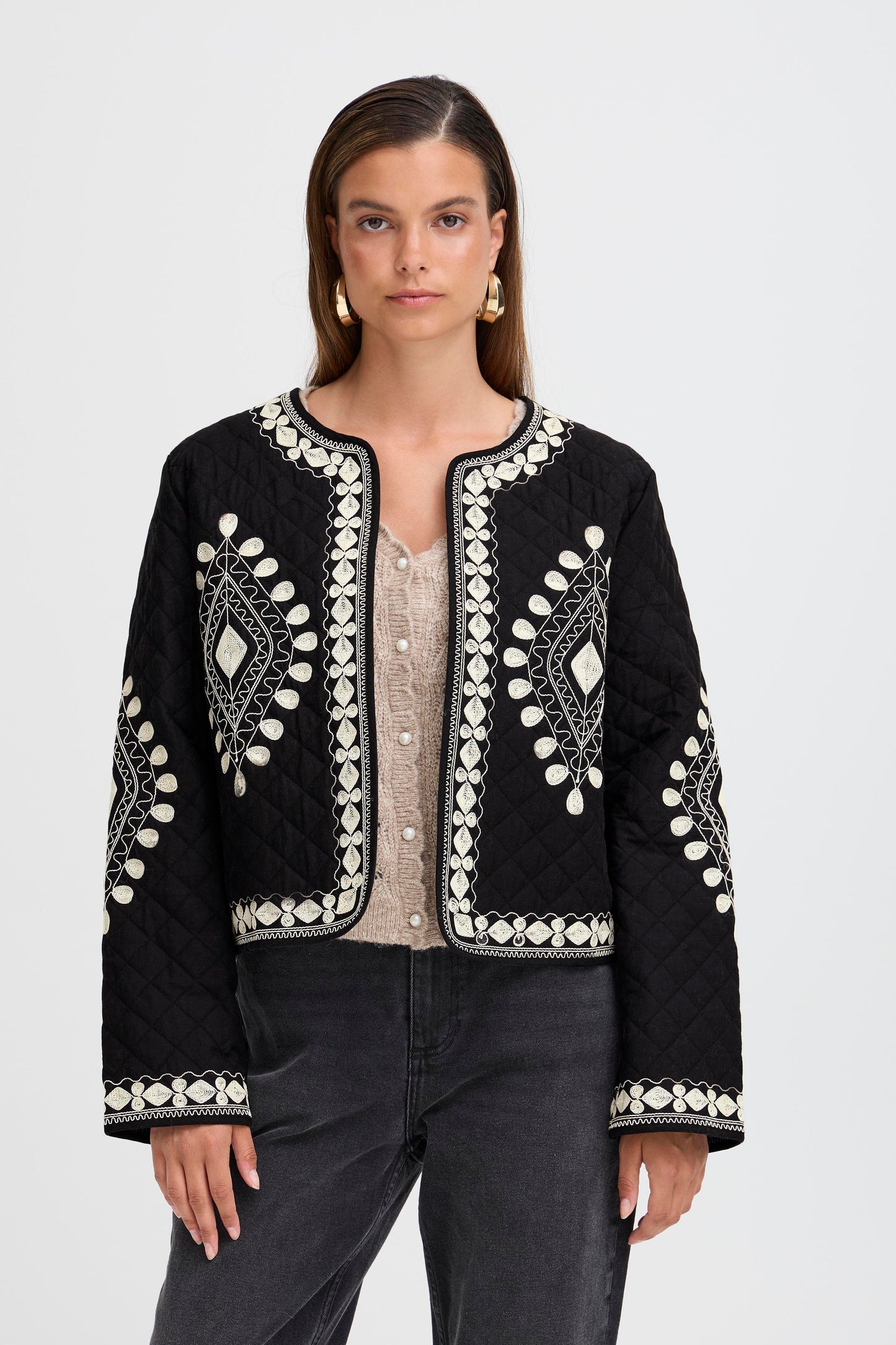Woman wearing a black embroidered jacket on a white background