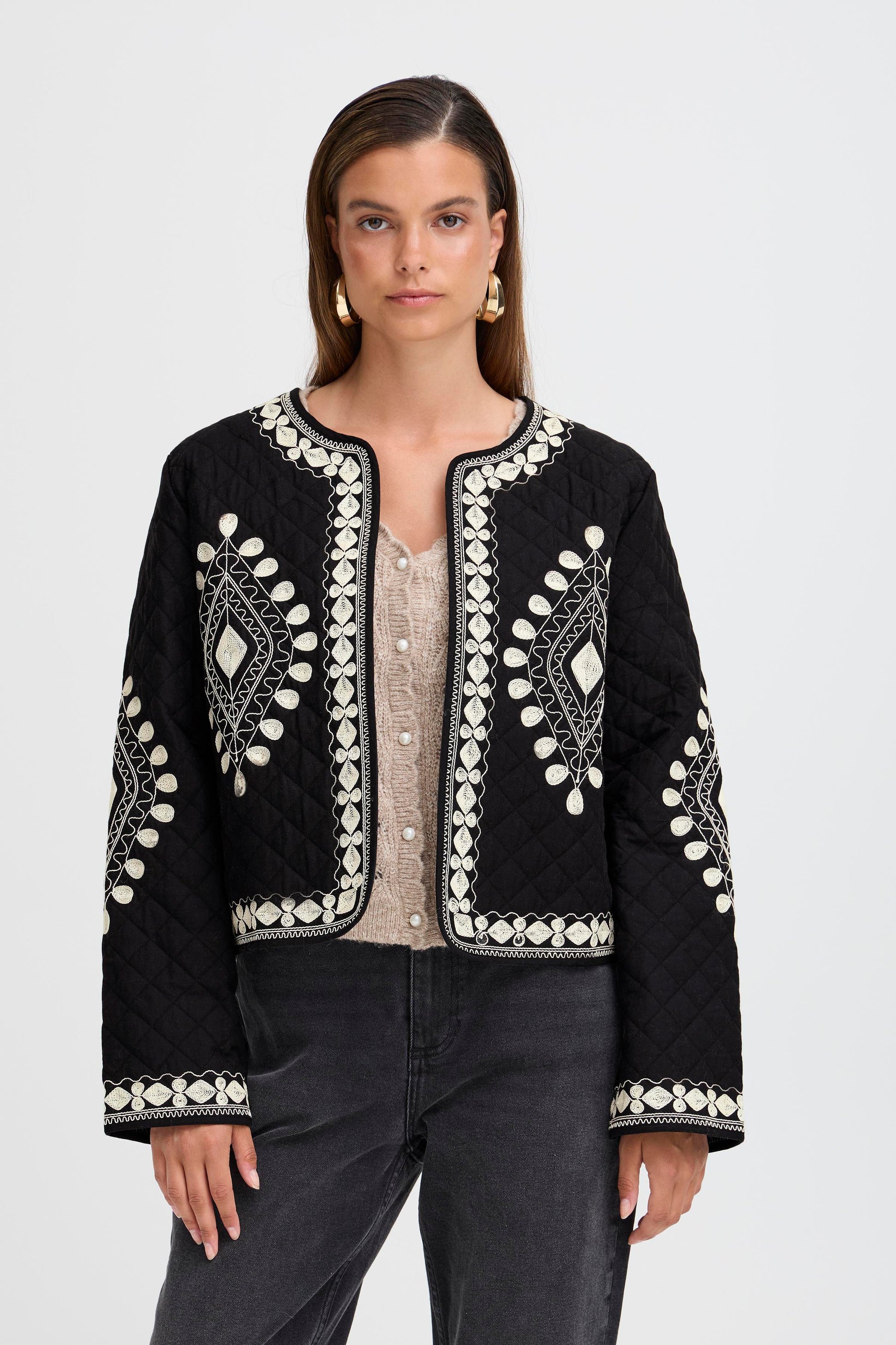 Woman wearing a black embroidered jacket on a white background