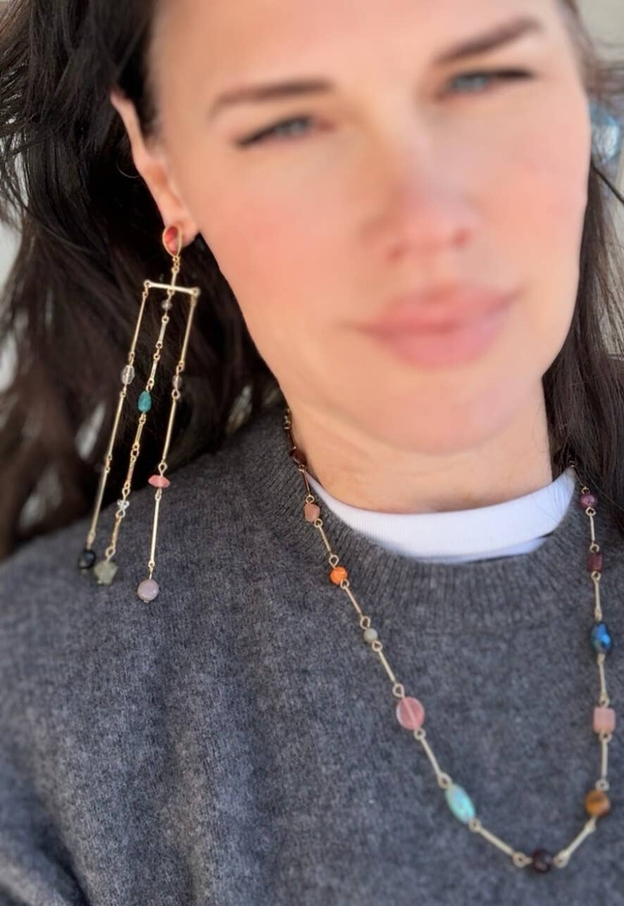 Person wearing a beaded necklace and earrings with a blurred background