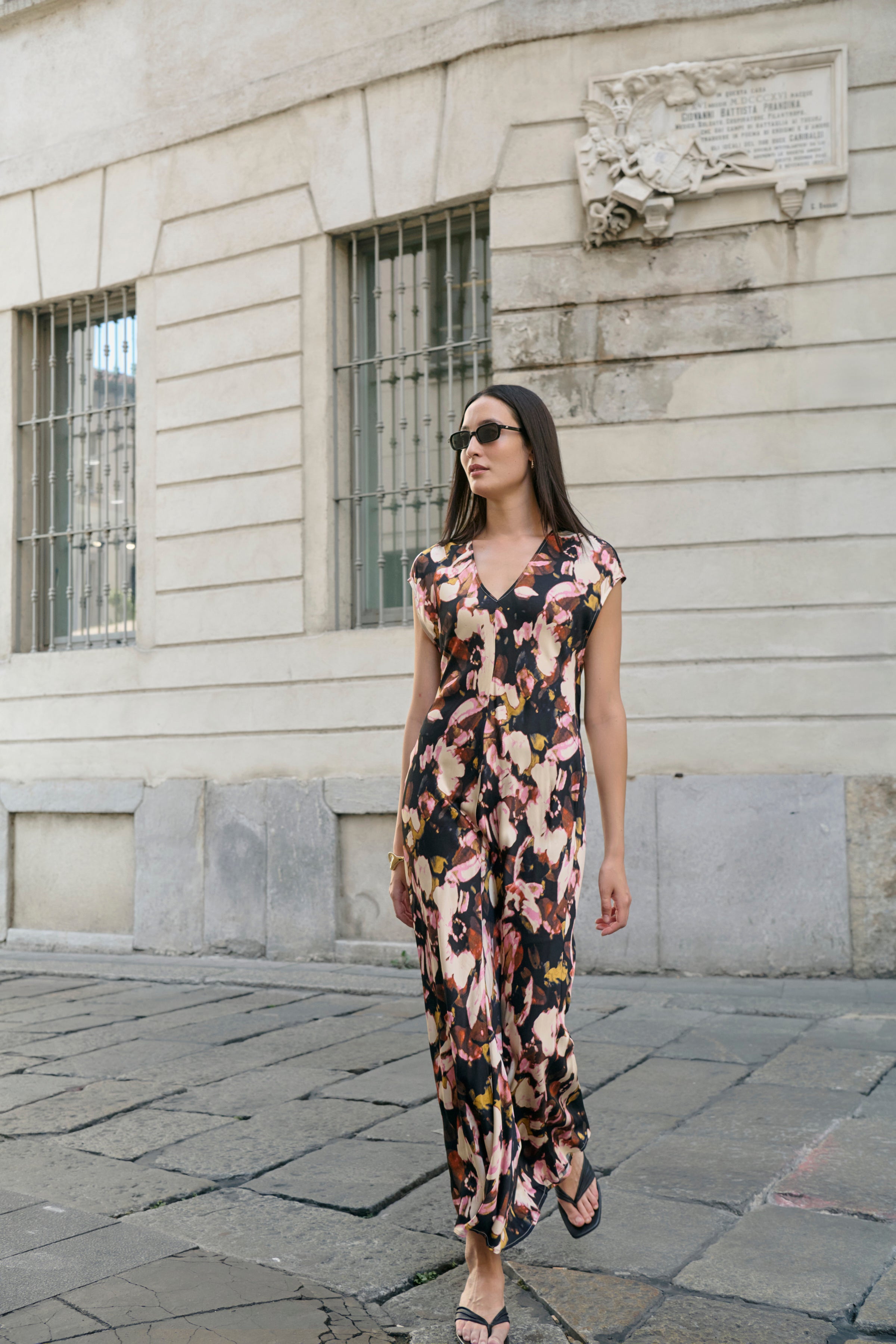 Woman in a floral dress standing on a street with a building in the background