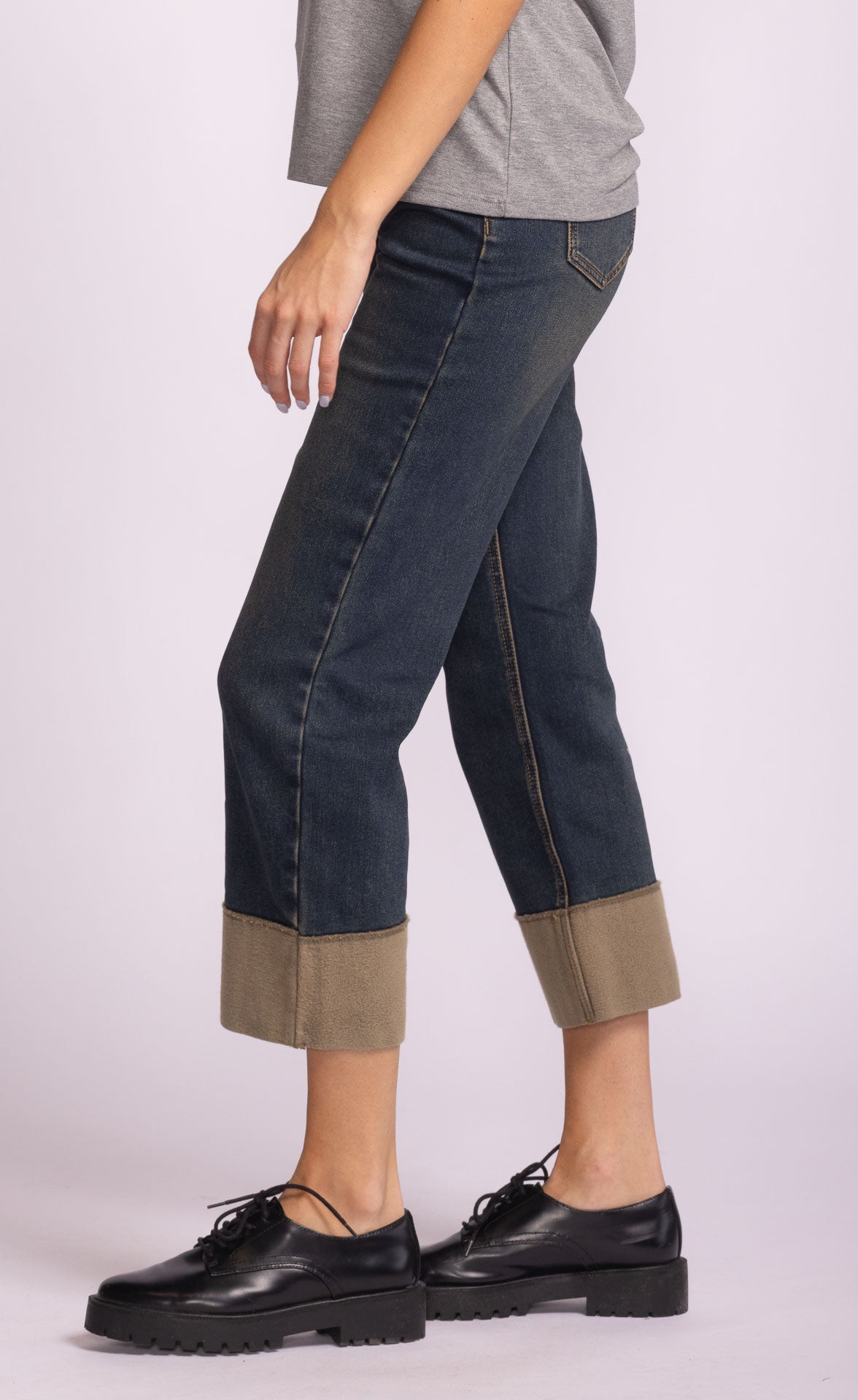 Dark blue jeans with rolled cuffs above the ankle worn by a woman 